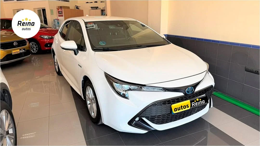 Toyota Corolla híbrido blanco visto en tres cuartos delantero dentro del concesionario Autos Reina en Mijas
