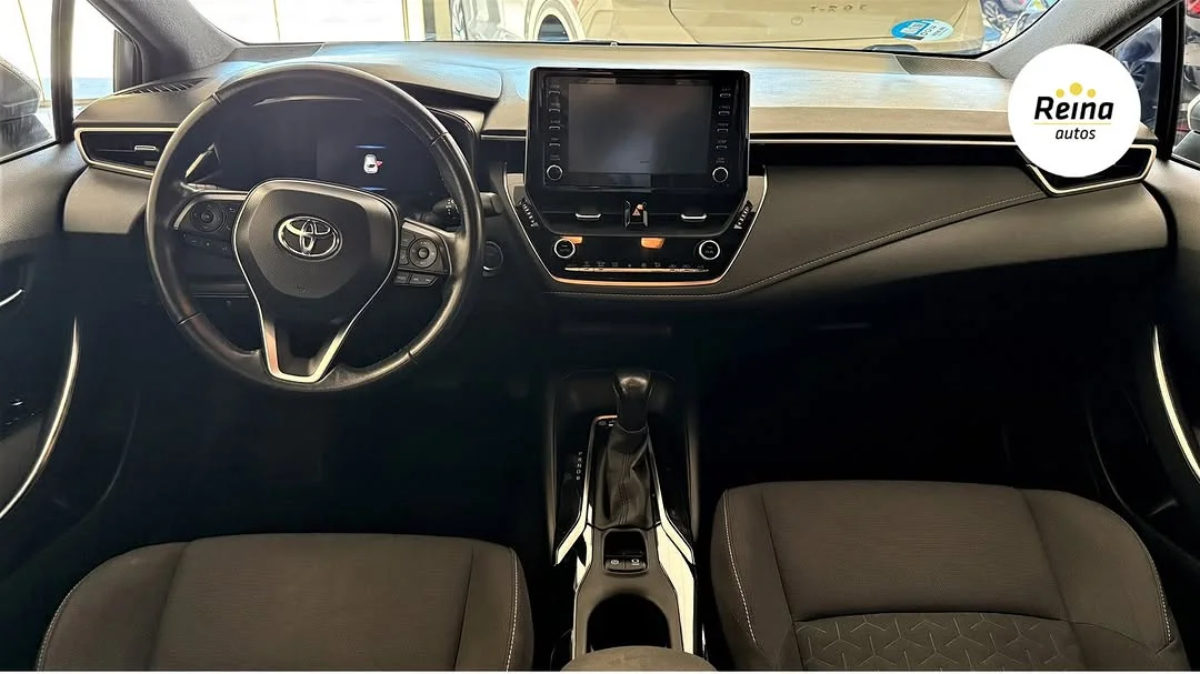 Vista interior del Toyota Corolla híbrido desde el asiento del conductor, con volante Toyota, pantalla central y palanca automática